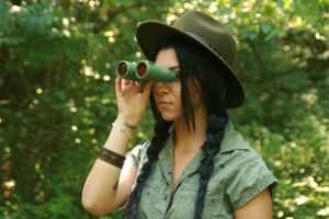 Person using binoculars for birdwatching in a natural woodland setting