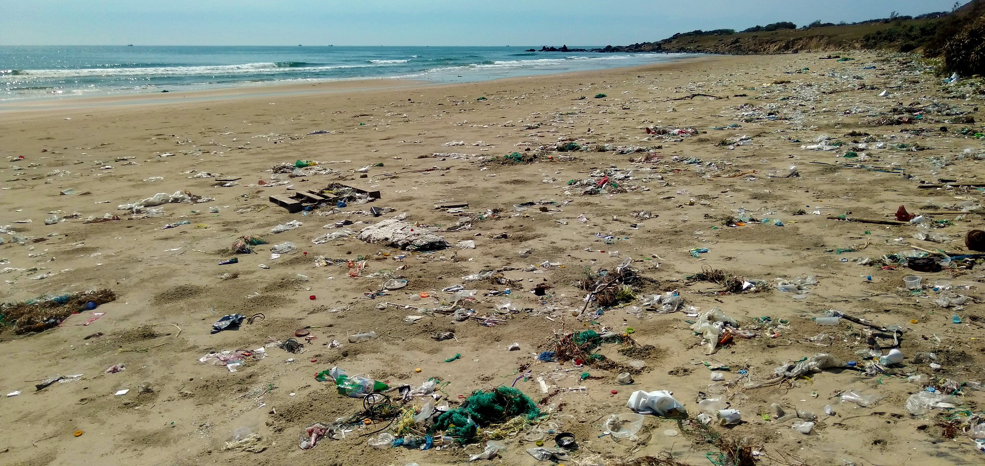 Plastic waste and debris scattered along a sandy ocean beach